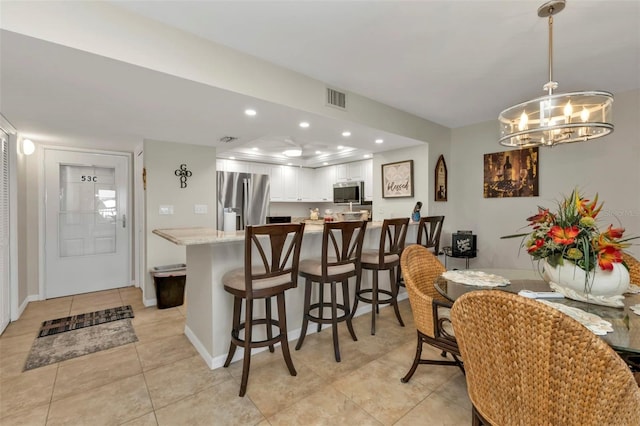 kitchen with stainless steel appliances, an inviting chandelier, light tile patterned flooring, white cabinetry, and decorative light fixtures