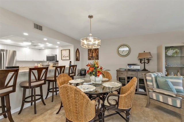 tiled dining space featuring an inviting chandelier and a raised ceiling