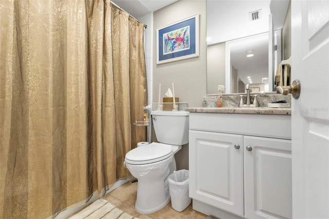 bathroom with toilet, vanity, and tile patterned floors