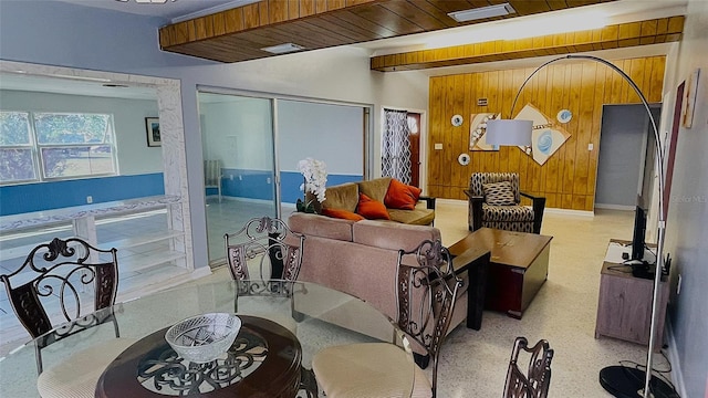 living room featuring wood walls and beamed ceiling