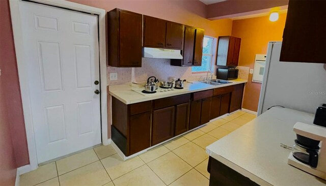 kitchen with white appliances, sink, dark brown cabinets, and light tile patterned flooring