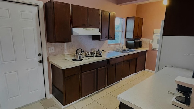 kitchen with light tile patterned floors, dark brown cabinets, sink, and tasteful backsplash