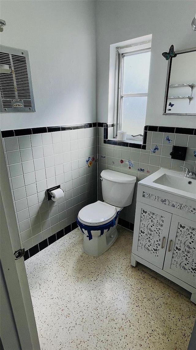 bathroom featuring vanity, toilet, and tile walls