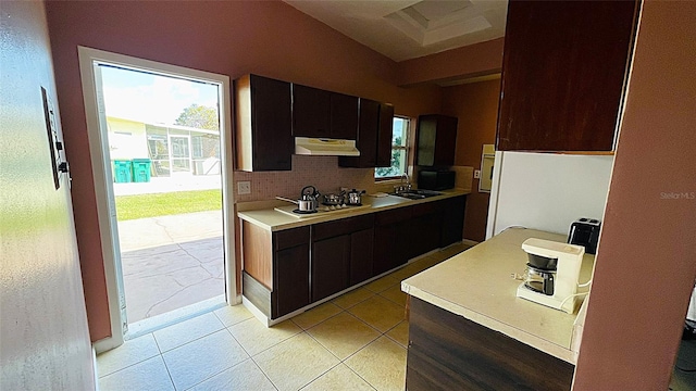 kitchen with tasteful backsplash, light tile patterned flooring, dark brown cabinetry, sink, and stainless steel gas cooktop