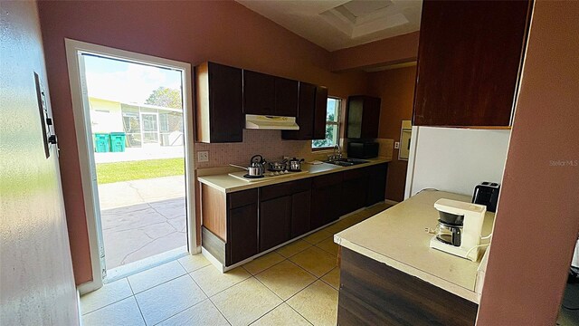 554 Lindley Ter, Port Charlotte, FL 33952 - kitchen with under cabinet range hood, backsplash, light countertops, cooktop, and light tile patterned flooring