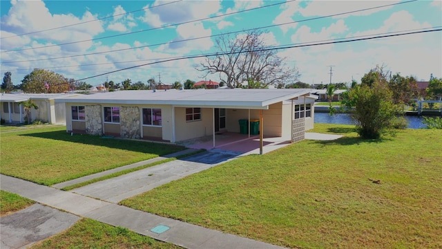 single story home featuring a front yard, a carport, and a water view