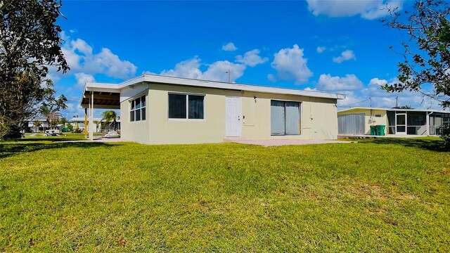 554 Lindley Ter, Port Charlotte, FL 33952 - rear view of house featuring a sunroom, a lawn, and stucco siding