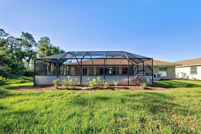 rear view of property featuring central AC, a lanai, and a lawn