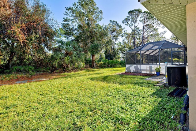 view of yard with central AC unit and a lanai