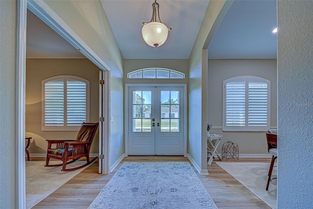 foyer entrance featuring lofted ceiling, light wood-type flooring, and french doors