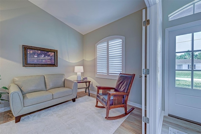 living room with plenty of natural light, light hardwood / wood-style floors, and lofted ceiling