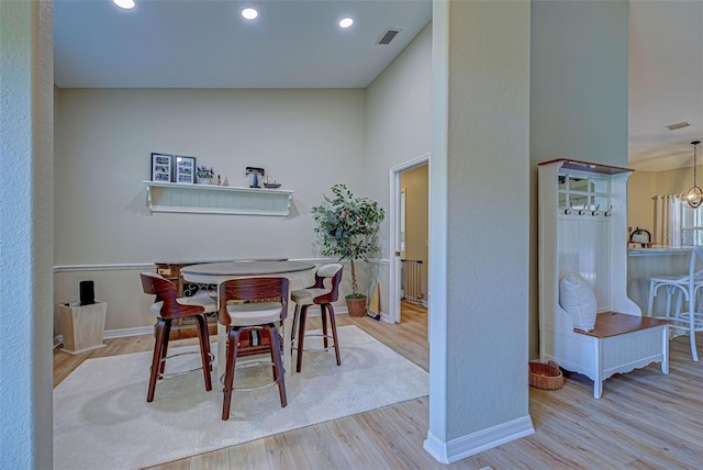 dining area with high vaulted ceiling, light hardwood / wood-style floors, and an inviting chandelier