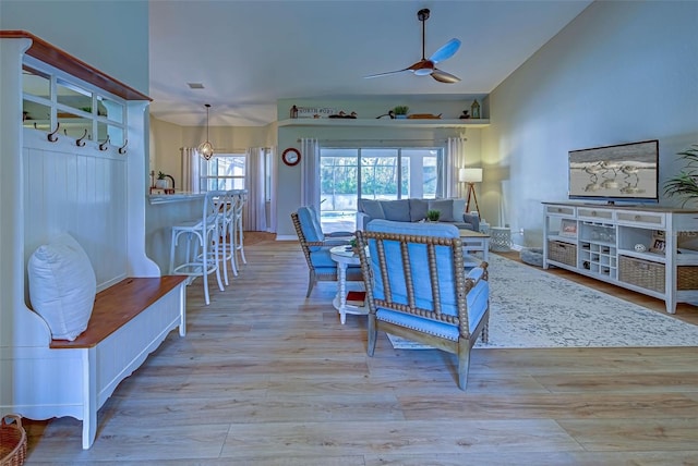 living room with ceiling fan, light hardwood / wood-style floors, and lofted ceiling