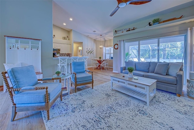 living room featuring ceiling fan, lofted ceiling, and light hardwood / wood-style flooring