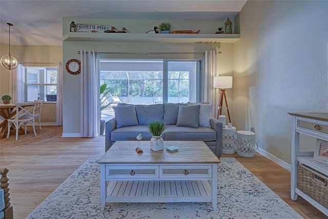 living room with a wealth of natural light, light hardwood / wood-style floors, and an inviting chandelier