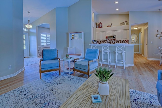 living room with high vaulted ceiling and light wood-type flooring