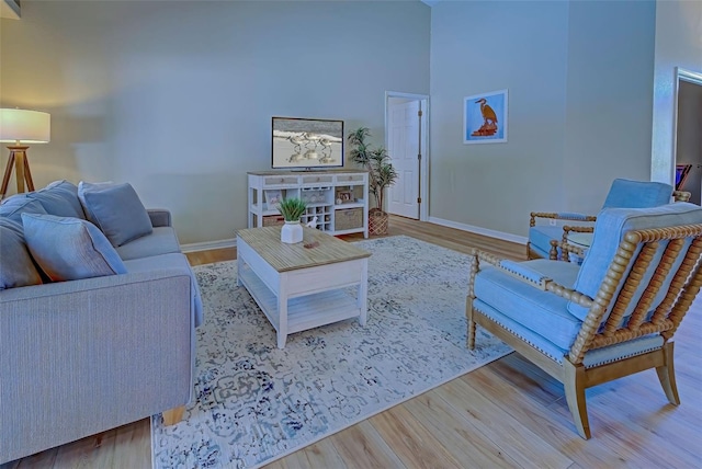 living room featuring light wood-type flooring and a towering ceiling