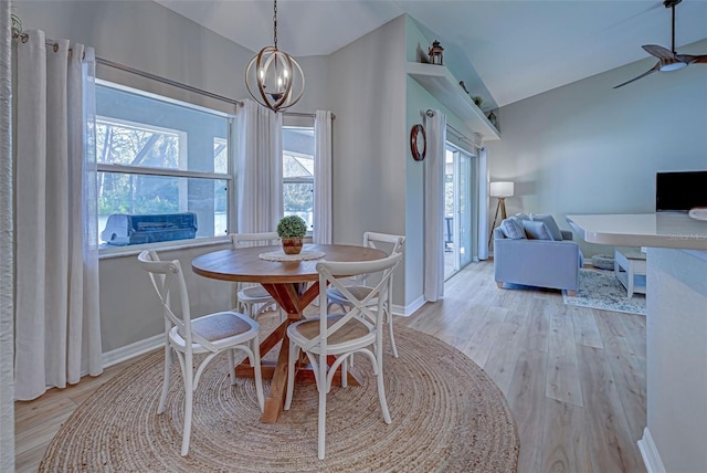 dining area with light hardwood / wood-style flooring, vaulted ceiling, and an inviting chandelier