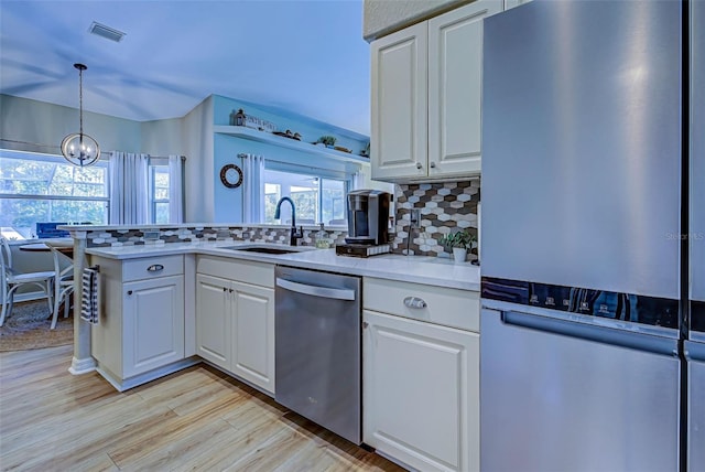 kitchen with appliances with stainless steel finishes, white cabinetry, pendant lighting, and sink