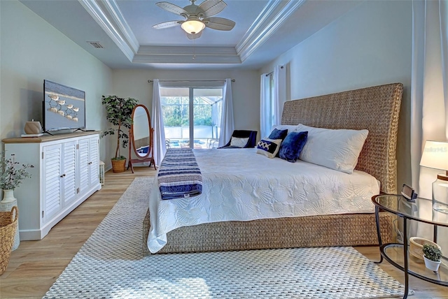 bedroom with access to exterior, light wood-type flooring, a raised ceiling, ceiling fan, and crown molding