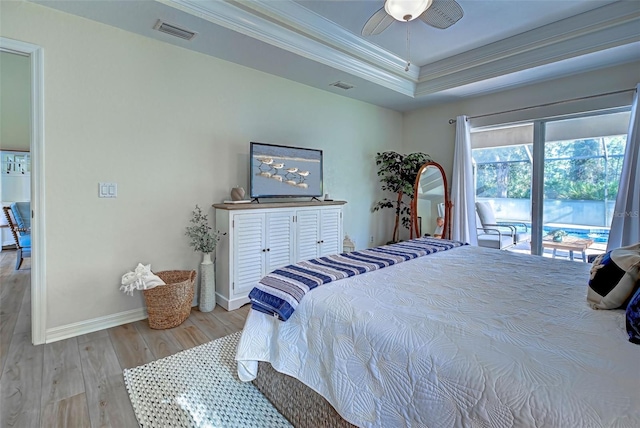 bedroom with access to exterior, ceiling fan, light hardwood / wood-style floors, a tray ceiling, and ornamental molding