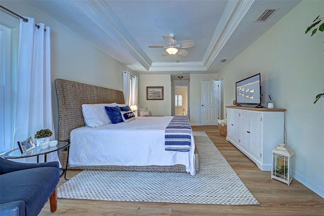 bedroom with a raised ceiling, ceiling fan, ornamental molding, and light wood-type flooring