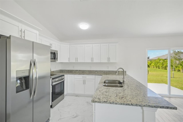 kitchen with appliances with stainless steel finishes, light stone countertops, sink, vaulted ceiling, and white cabinets