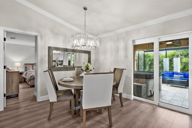 dining space with wood-type flooring, a chandelier, and ornamental molding