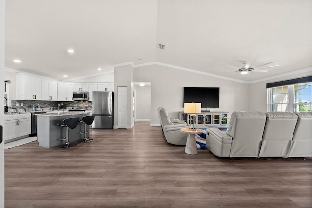 living room featuring hardwood / wood-style flooring, ceiling fan, vaulted ceiling, and ornamental molding