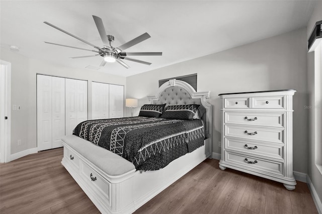 bedroom featuring dark hardwood / wood-style flooring, ceiling fan, and two closets