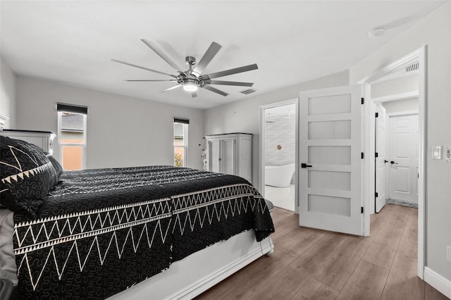 bedroom featuring multiple windows, hardwood / wood-style floors, ceiling fan, and ensuite bathroom