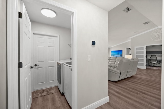 clothes washing area featuring washing machine and dryer, hardwood / wood-style floors, and ornamental molding