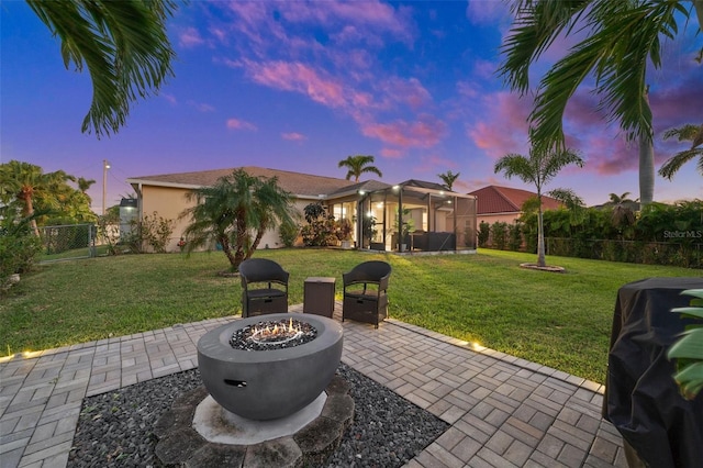 patio terrace at dusk featuring a grill, an outdoor fire pit, and a yard