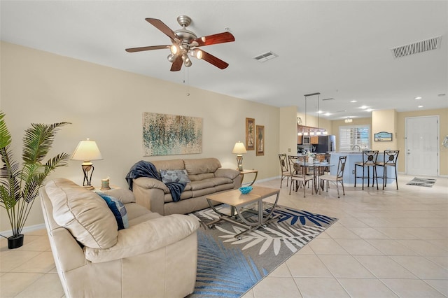 living room with light tile patterned flooring and ceiling fan with notable chandelier