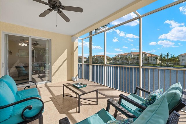 sunroom with ceiling fan and a water view