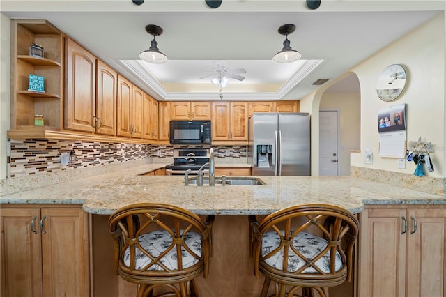 kitchen featuring stainless steel appliances, a raised ceiling, pendant lighting, sink, and kitchen peninsula