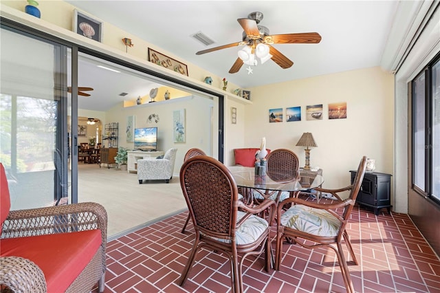 dining room featuring a wood stove, lofted ceiling, and ceiling fan