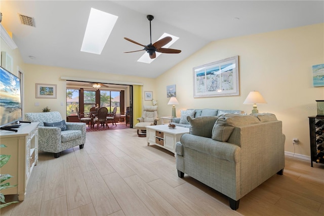 living room featuring light wood-type flooring, ceiling fan, and vaulted ceiling with skylight