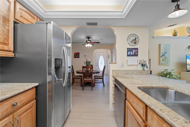 kitchen with stainless steel appliances, light stone counters, ceiling fan, decorative light fixtures, and light wood-type flooring