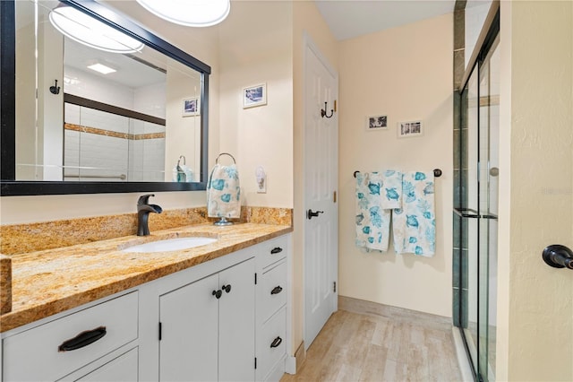 bathroom featuring walk in shower, vanity, and hardwood / wood-style flooring