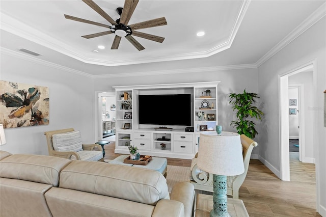 living room featuring ceiling fan, light hardwood / wood-style flooring, crown molding, and a tray ceiling