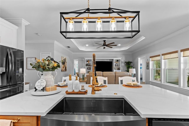 kitchen featuring ornamental molding, black refrigerator with ice dispenser, sink, and light stone counters