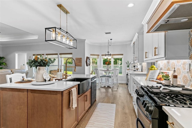 kitchen featuring stainless steel appliances, white cabinetry, extractor fan, sink, and a center island with sink