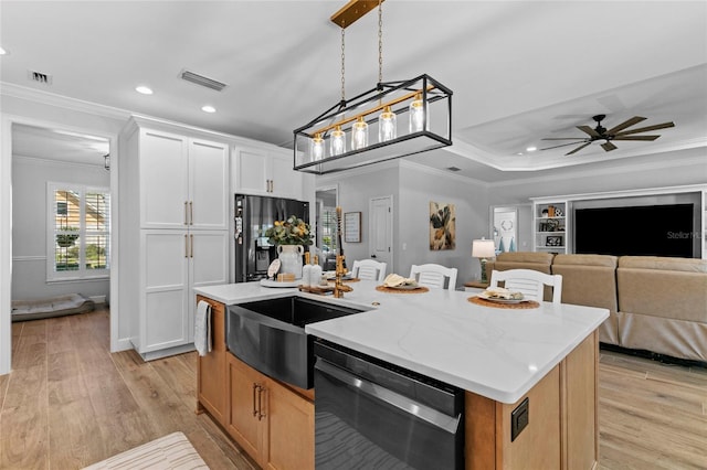 kitchen featuring a center island with sink, white cabinetry, light wood-type flooring, black dishwasher, and light stone countertops