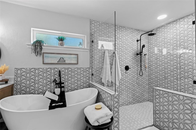 bathroom with shower with separate bathtub and tile walls