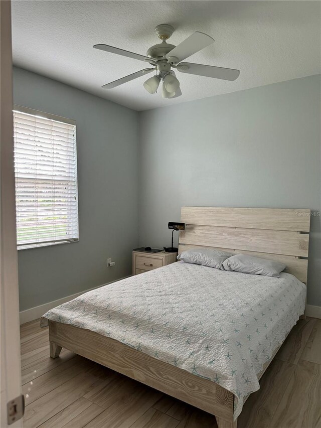 5101 Pine Shadow Ln, North Port, FL 34287 - bedroom with baseboards, ceiling fan, a textured ceiling, and wood finished floors