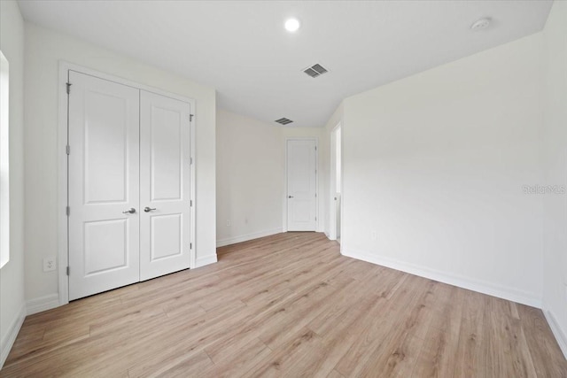 unfurnished bedroom with light hardwood / wood-style flooring and a closet