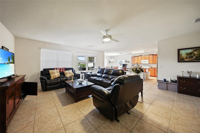 tiled living room with ceiling fan with notable chandelier