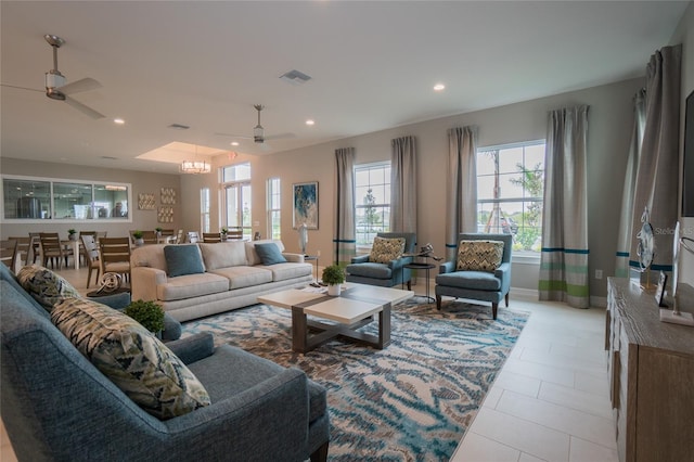 tiled living room featuring ceiling fan with notable chandelier