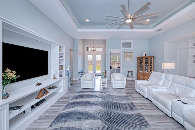 living room with hardwood / wood-style floors, ceiling fan, a tray ceiling, and french doors